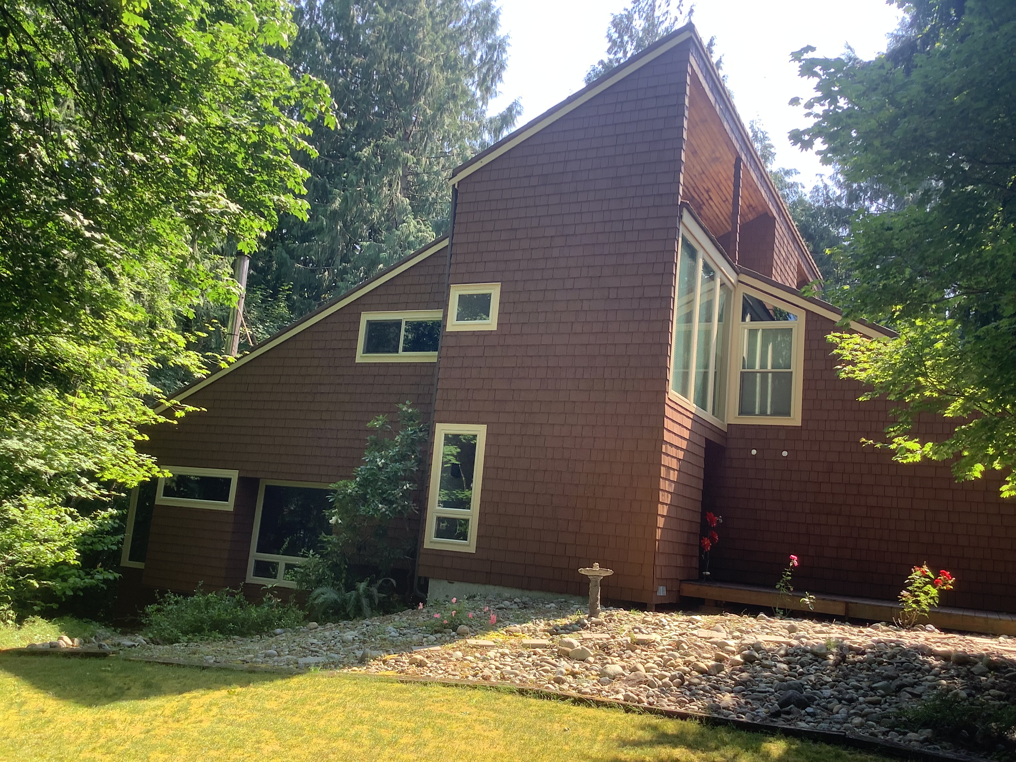 Stained cedar shake home with cream window trim and tall gable windows