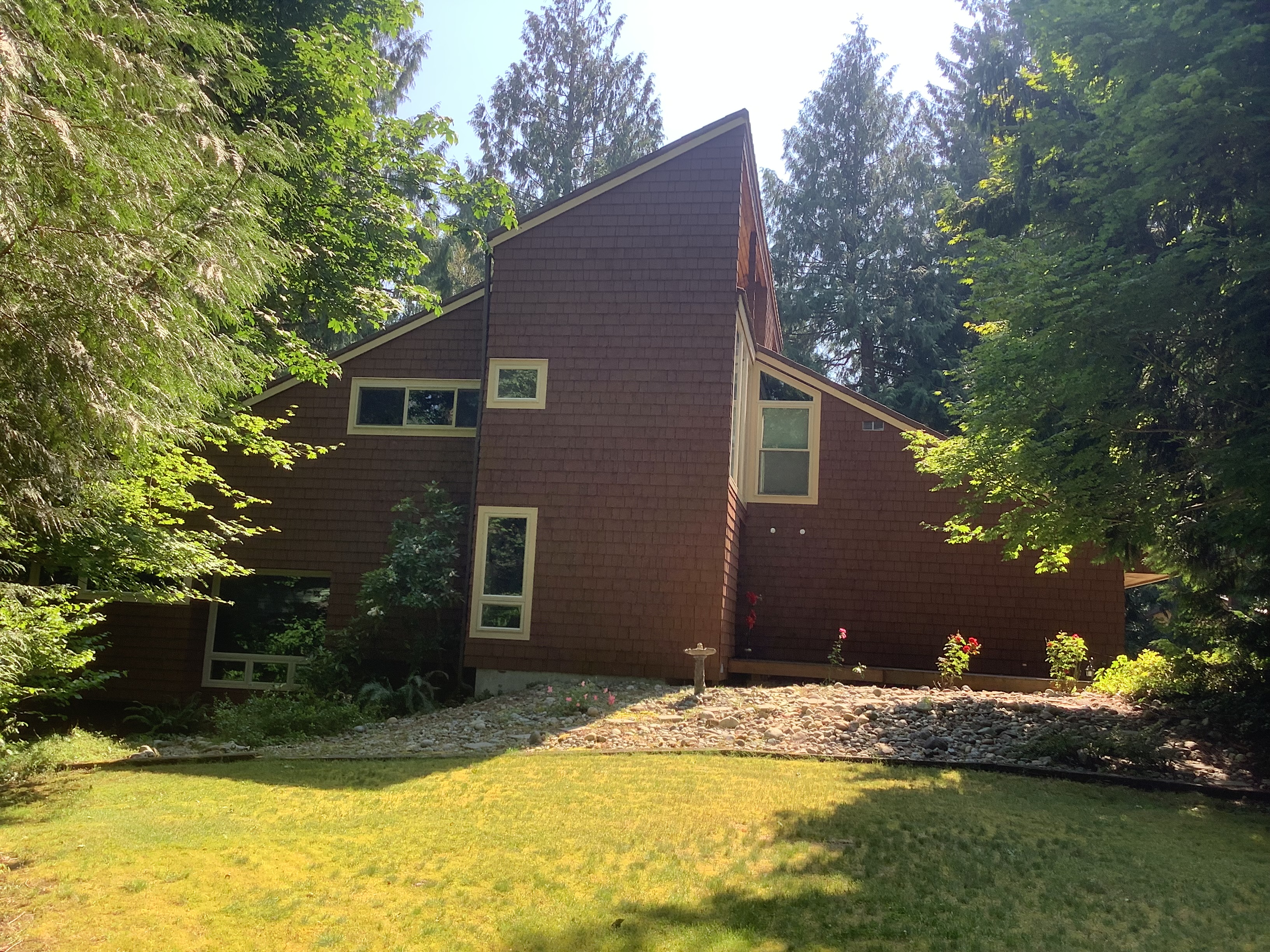 Exterior staining on a cedar shake home set among evergreen trees