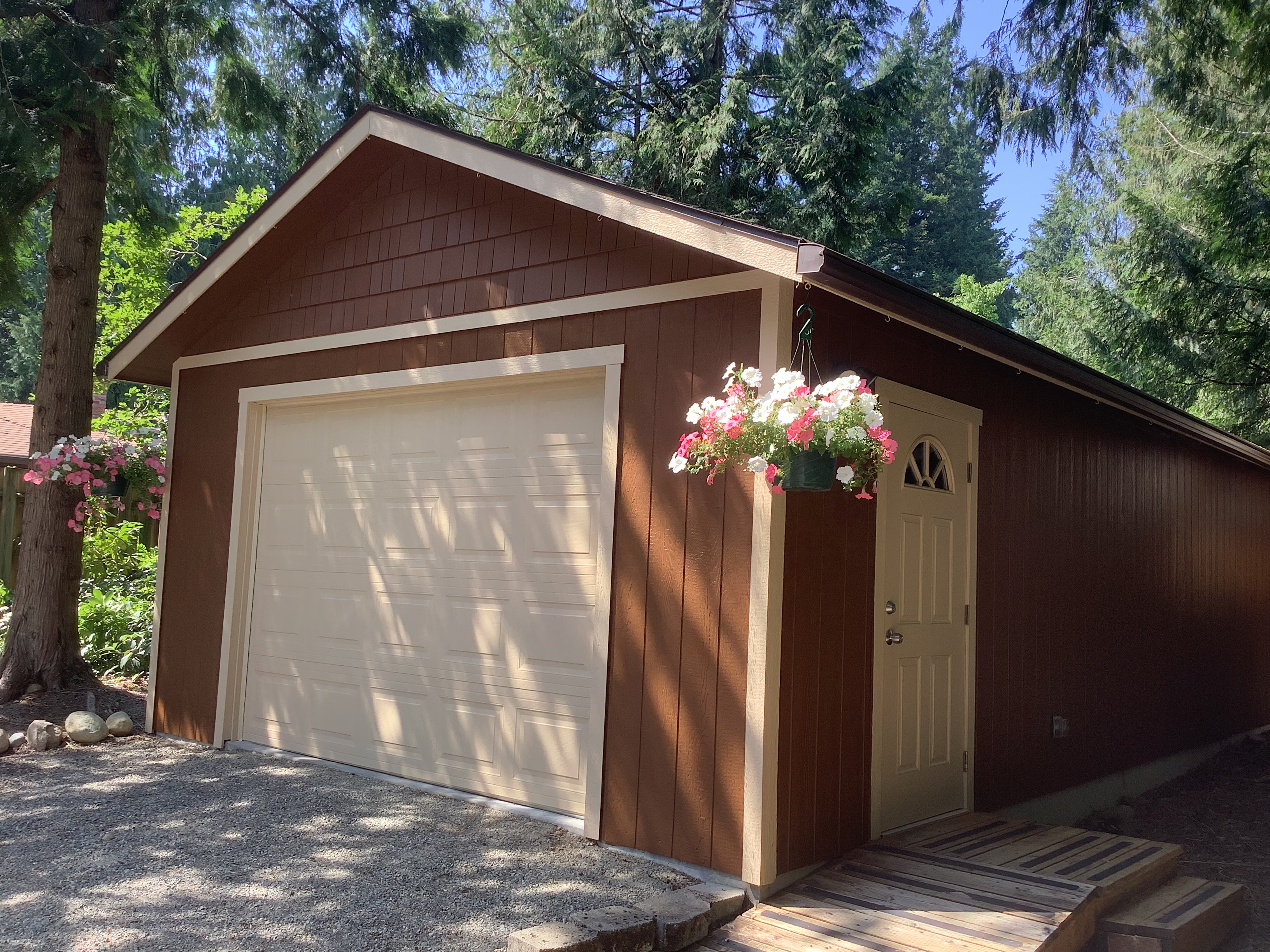 Brown garage with cream door, trim, and hanging flowers